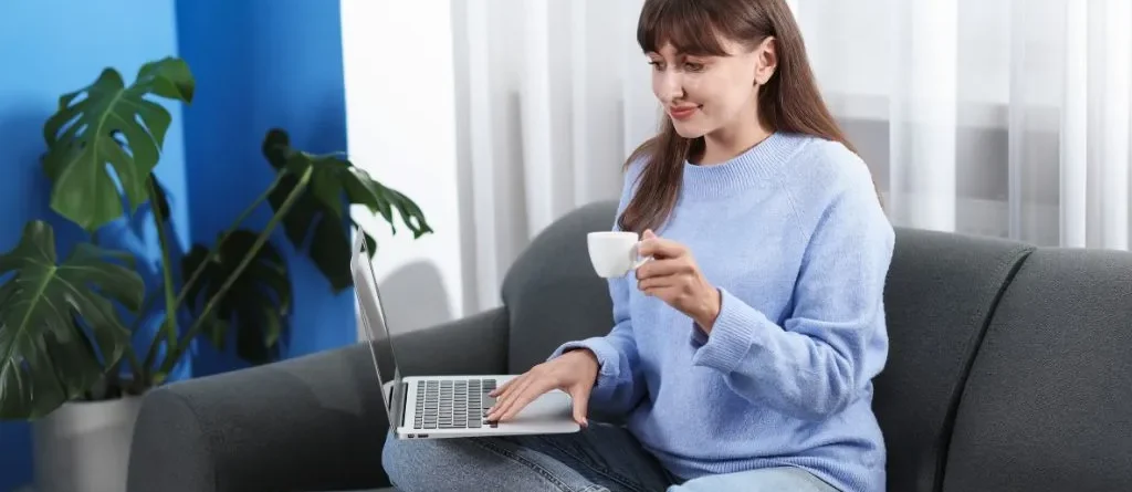 Mulher sentada no sofá com notebook no colo fazendo terapia online