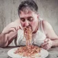 pessoa sentada na mesa comendo com compulsão alimentar